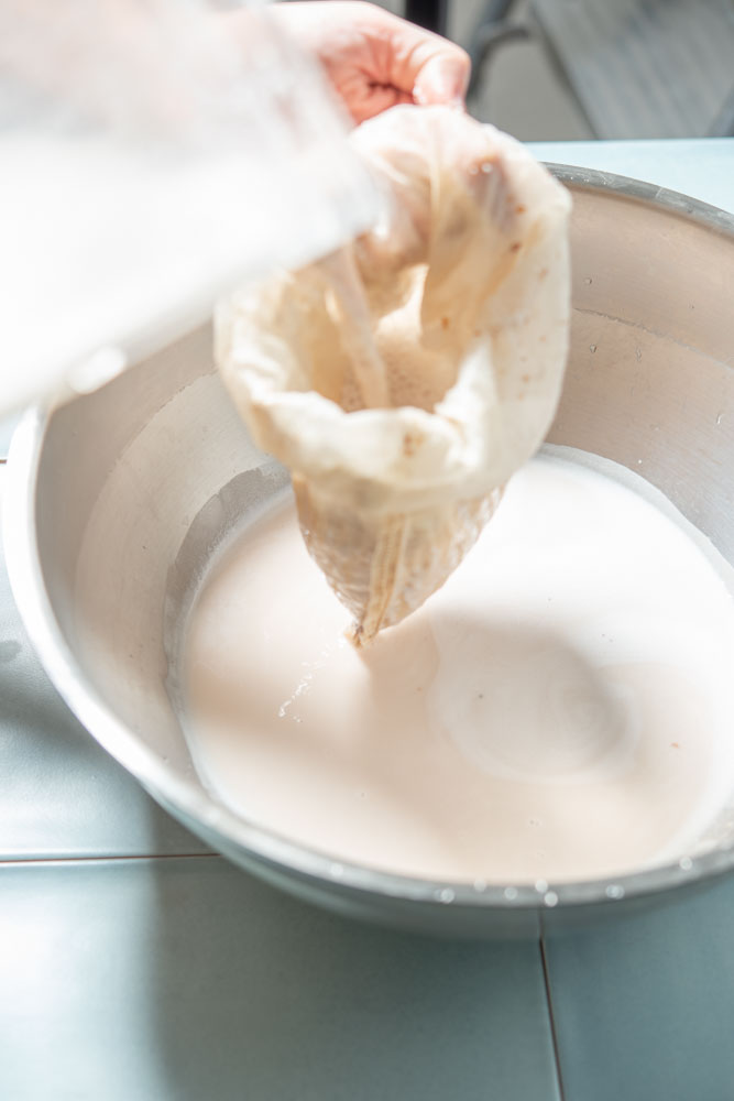 straining almond pulp through nutmilk bag
