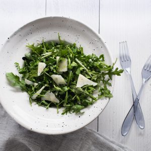 arugula salad in a bowl with Romano cheese on top