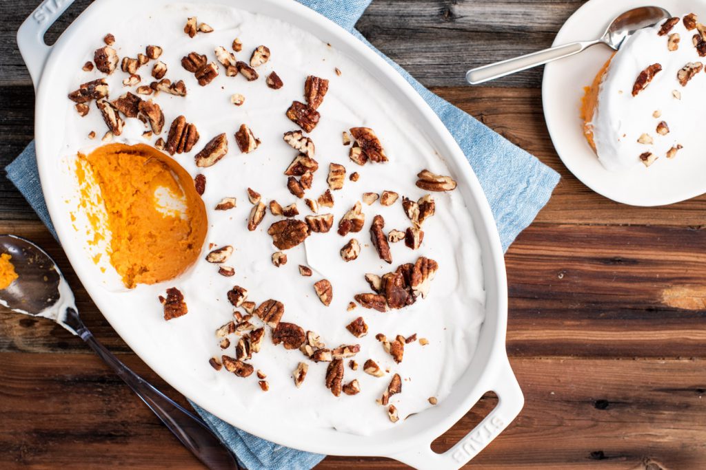 sweet potato casserole with coconut whipped cream on top and maple candied pecans as garnish