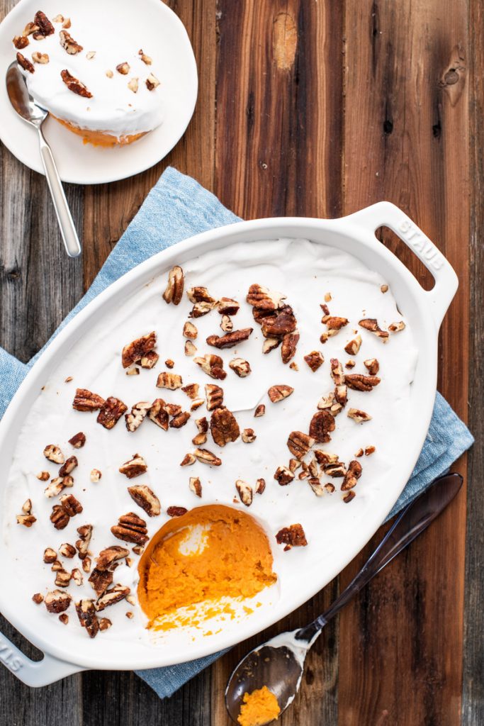 sweet potato casserole topped with coconut whipped cream and candied pecans