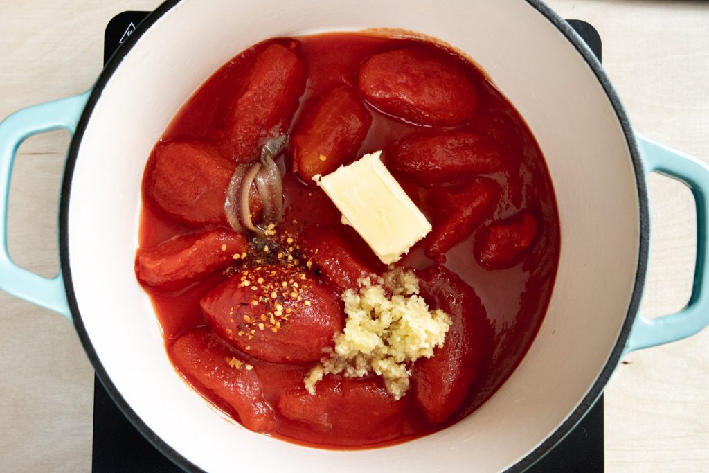 canned roma tomatoes, anchovy fillets, butter, garlic, and red pepper flakes in Dutch oven