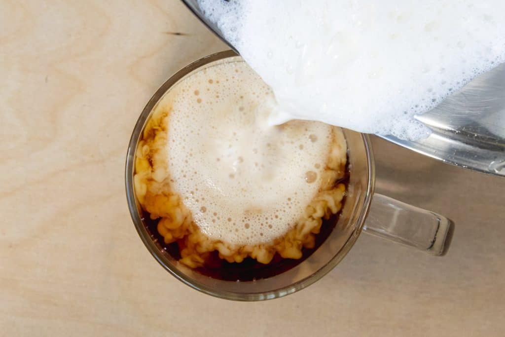 foamed half and half being poured into Earl Grey tea