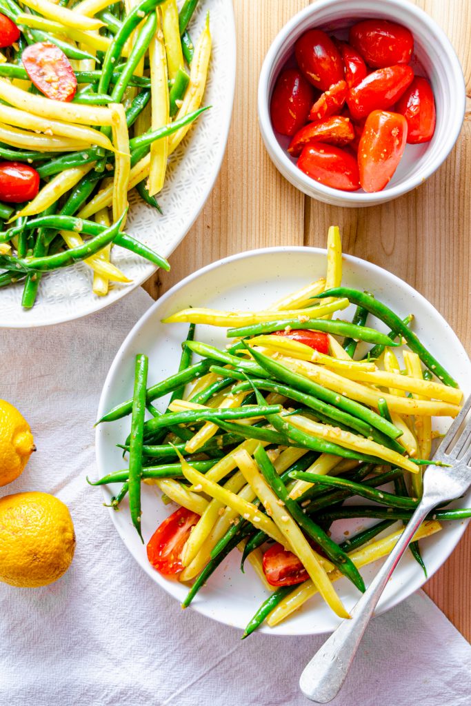 green and yellow green bean salad on a plate with cherry tomatoes