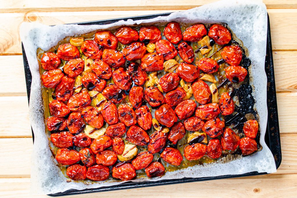 cherry tomatoes roasted on a tray with balsamic drizzle