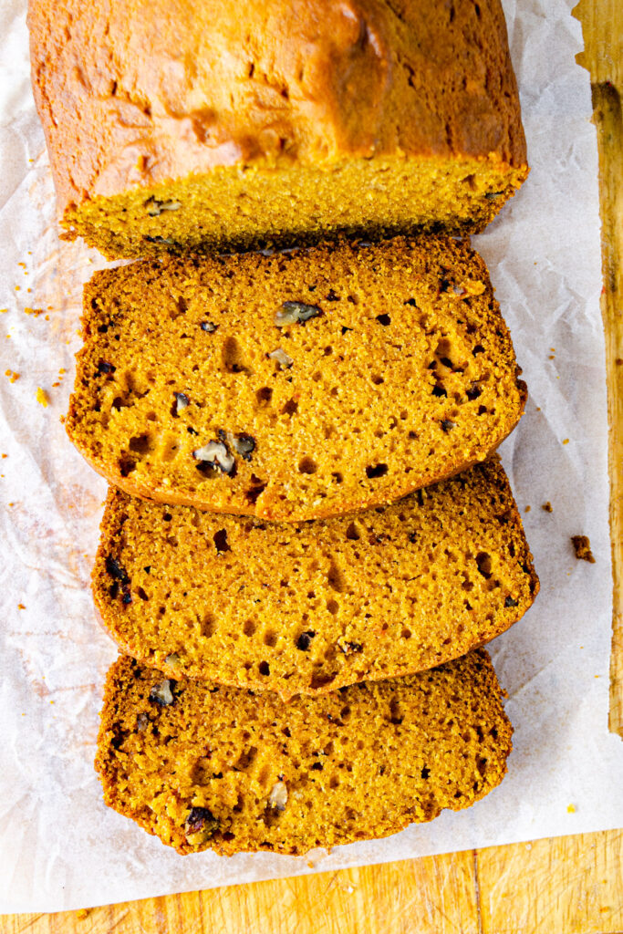 pumpkin bread sliced on parchment paper with nuts