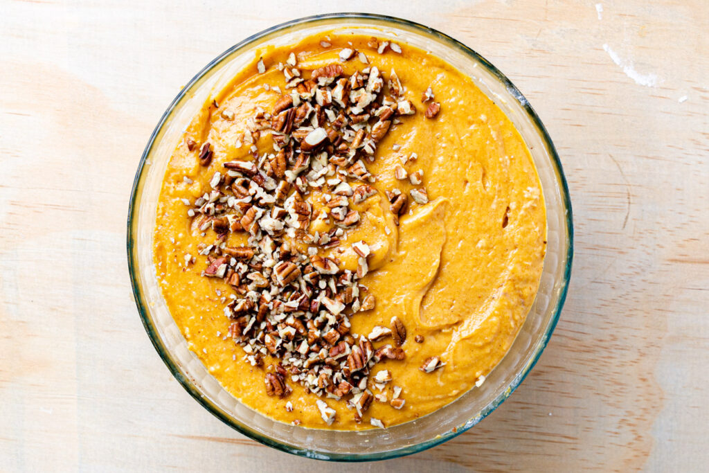 pumpkin bread batter in bowl with chopped nuts