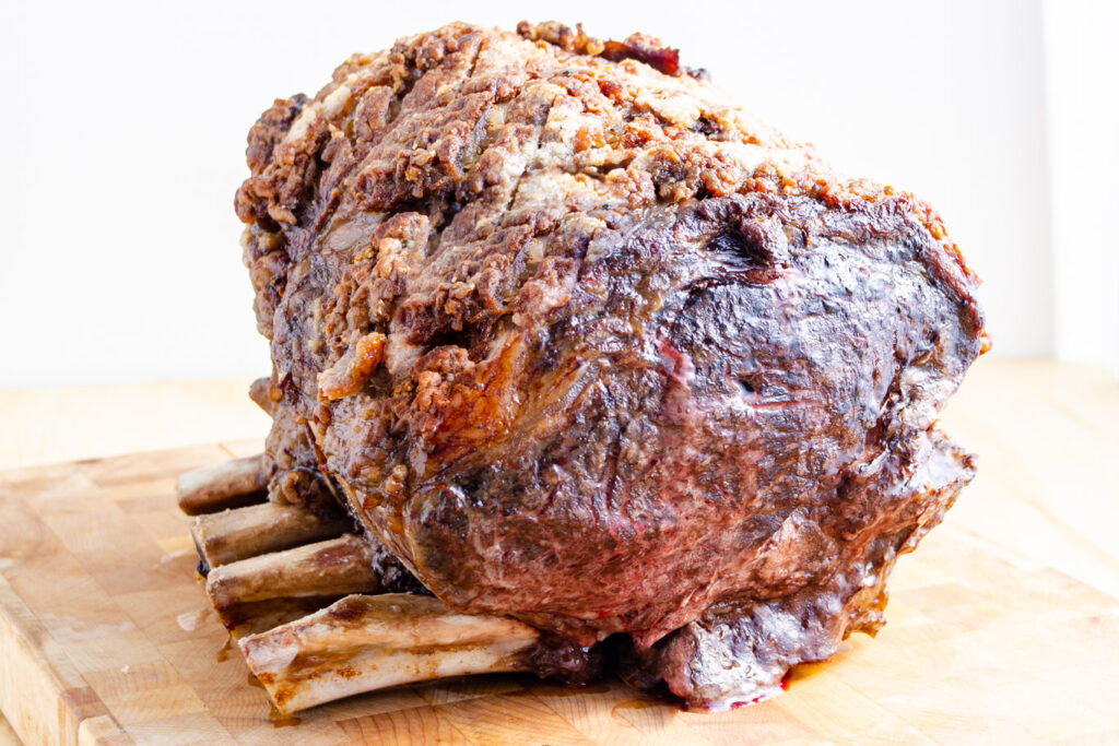 Brown prime rib roast on cutting board with bones in