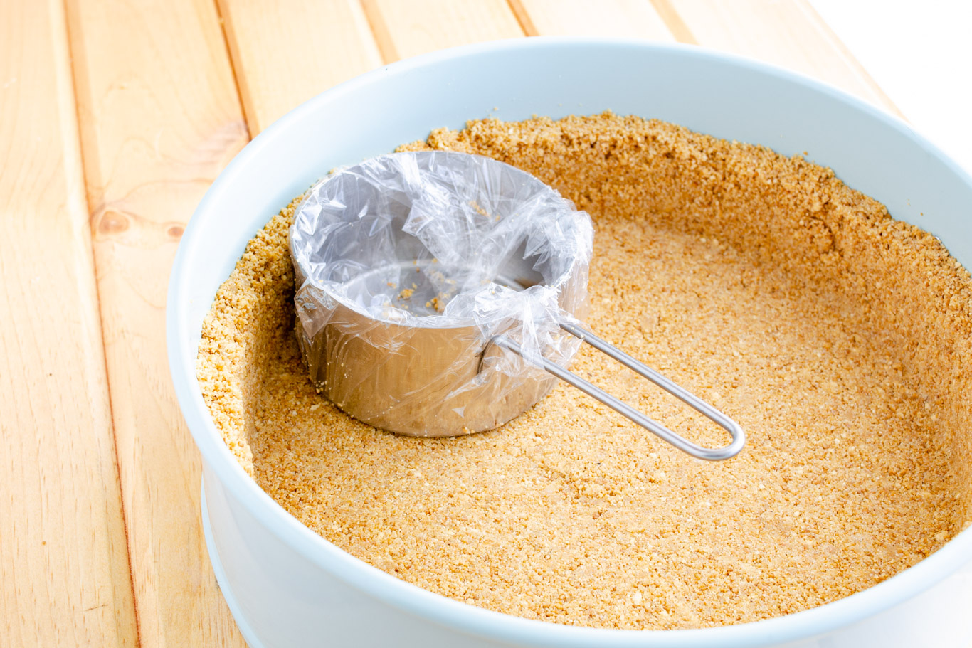 pressing homemade graham cracker crumbs into springform pan
