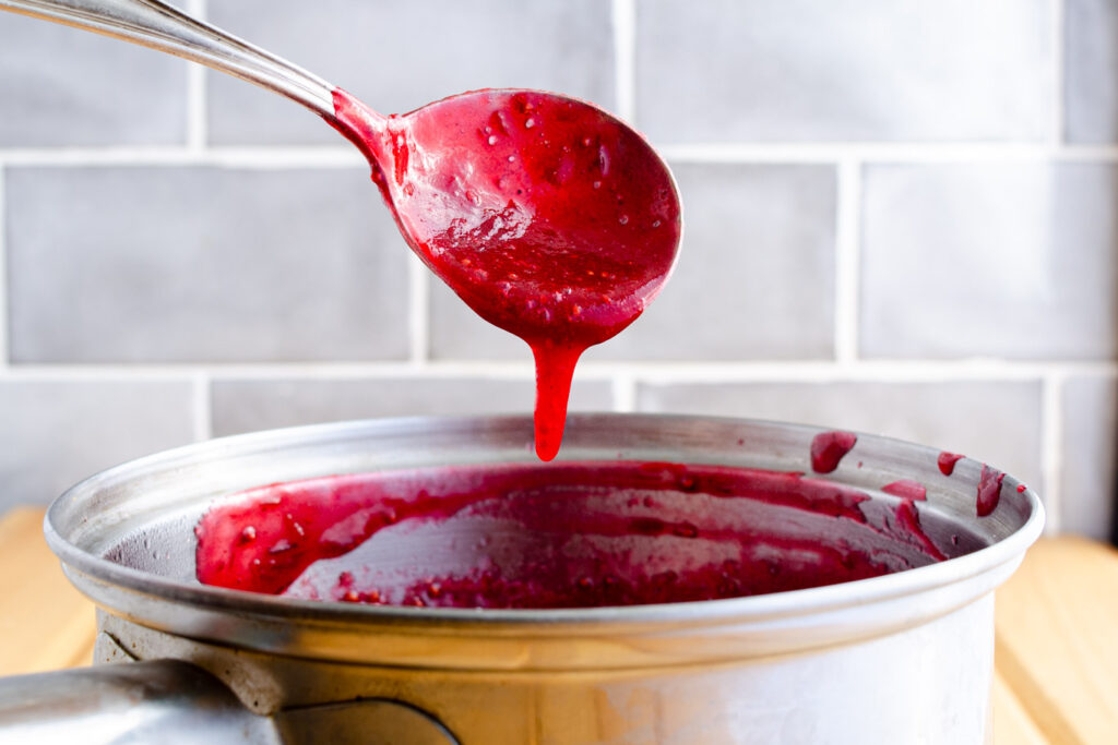 cranberry coulis sauce dripping off spoon over pot
