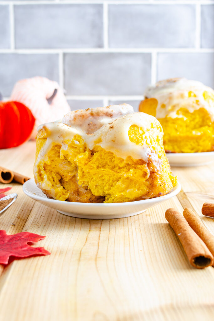 pumpkin cinnamon roll on plate with cream cheese icing