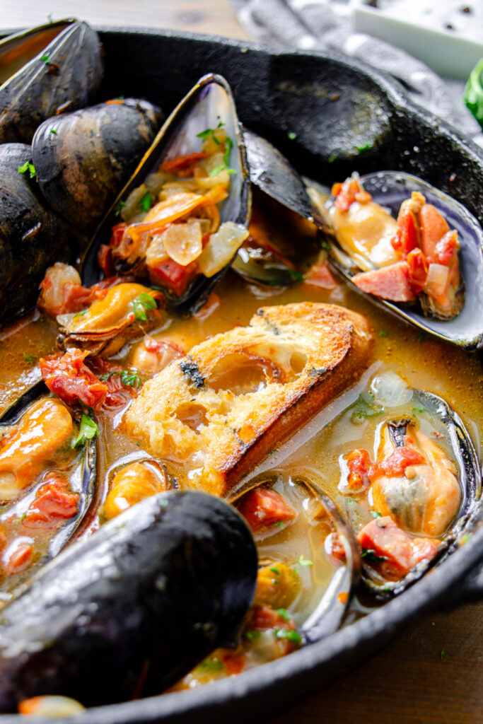 beer braised mussels in broth with sun dried tomatoes and spicy salami