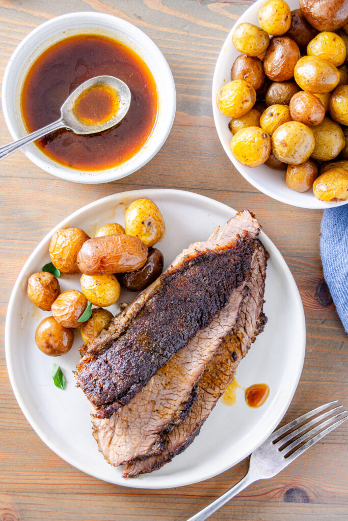 sliced brisket with juices served with baby potatoes