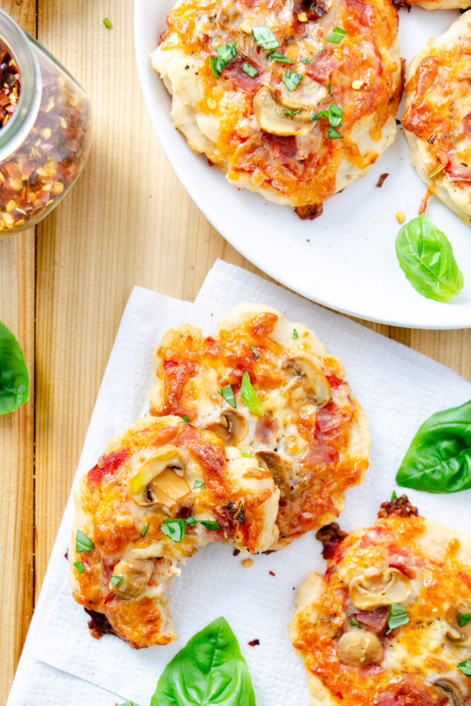 bite sized gluten-free pizzas topped with shredded mozzarella, mushrooms, and salami 