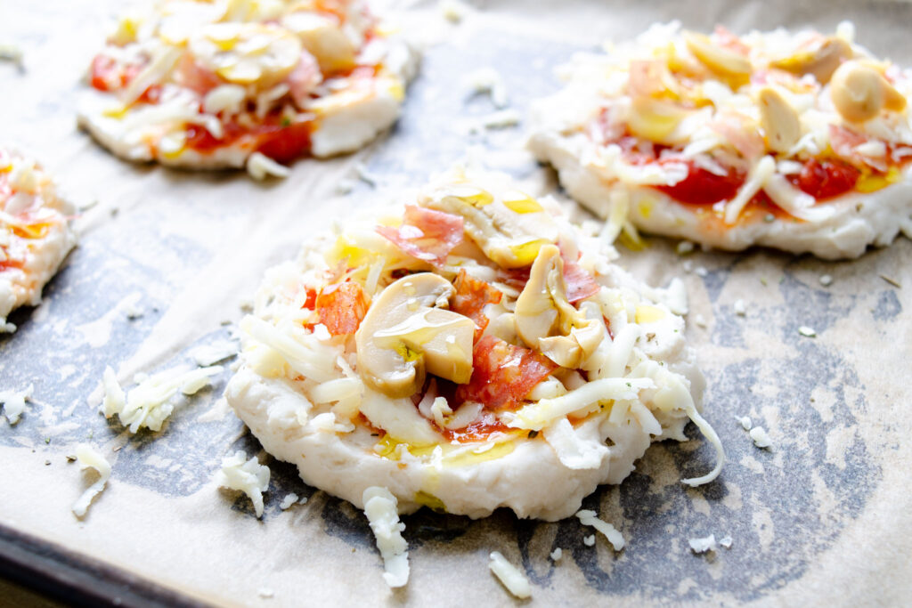 gluten-free pizza dough with homemade pizza sauce, mozzarella, salami, and mushrooms
